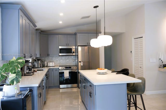 kitchen featuring pendant lighting, a center island, lofted ceiling, backsplash, and appliances with stainless steel finishes