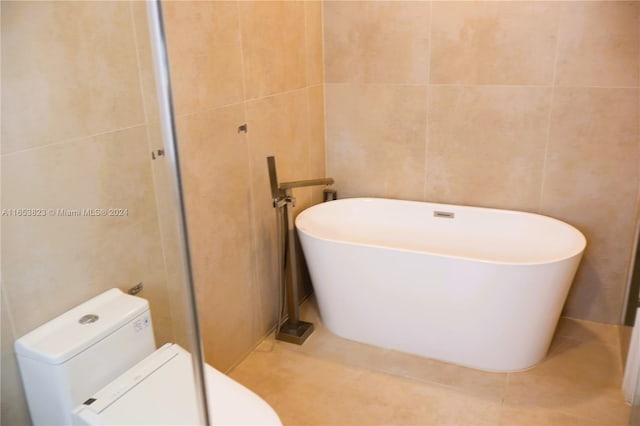 bathroom featuring tile walls, a bath, and toilet