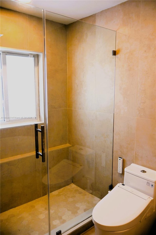 bathroom with tile walls, a shower with door, and toilet