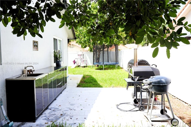 view of yard with a trampoline, sink, and a patio area