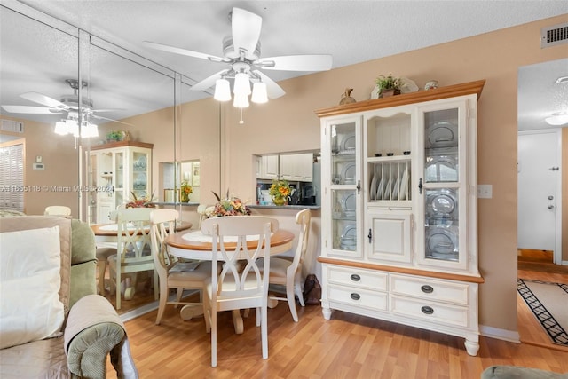 dining room featuring light wood-type flooring, ceiling fan, and a textured ceiling