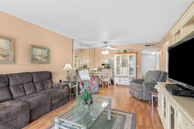 living room featuring a textured ceiling, ceiling fan, and light hardwood / wood-style floors