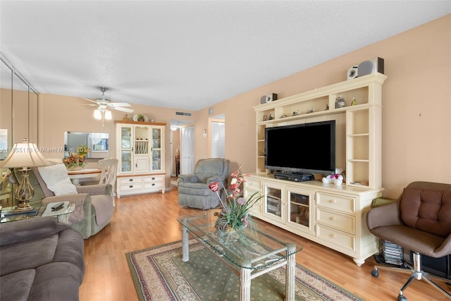 living room featuring a textured ceiling, light hardwood / wood-style flooring, and ceiling fan