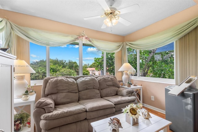 living room with ceiling fan, plenty of natural light, wood-type flooring, and a textured ceiling