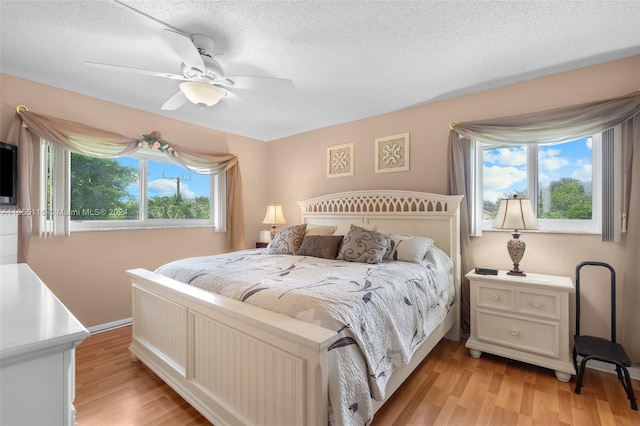 bedroom featuring ceiling fan, light wood-type flooring, and multiple windows