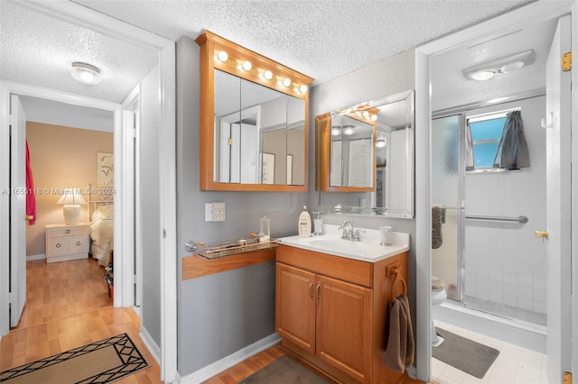 bathroom with an enclosed shower, hardwood / wood-style flooring, a textured ceiling, and vanity