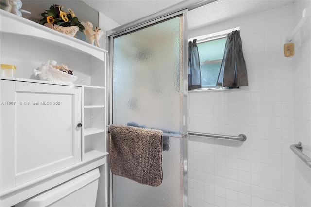 bathroom featuring a shower with door and a textured ceiling