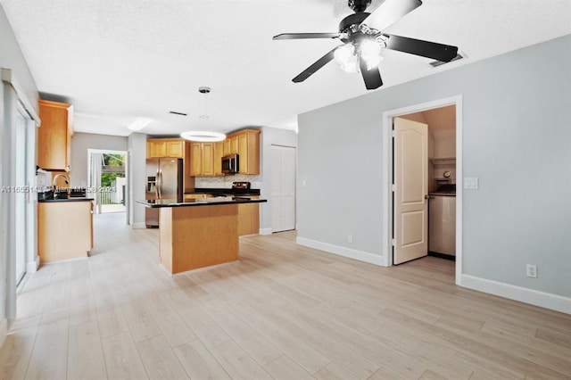 kitchen with ceiling fan, light wood-type flooring, decorative light fixtures, a kitchen island, and stainless steel appliances