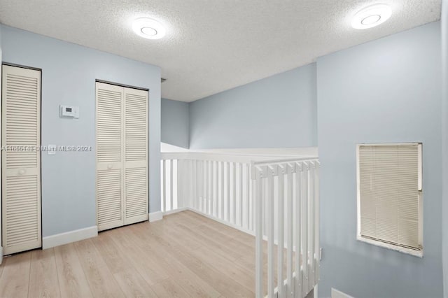 hall with light hardwood / wood-style flooring and a textured ceiling