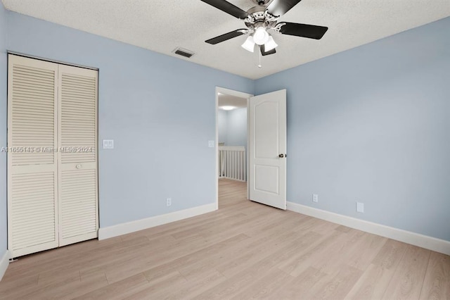 unfurnished bedroom with a textured ceiling, a closet, light hardwood / wood-style floors, and ceiling fan