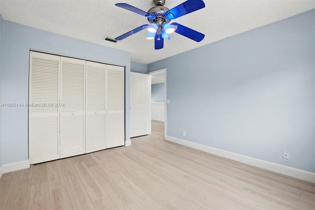 unfurnished bedroom with ceiling fan, light hardwood / wood-style floors, a textured ceiling, and a closet