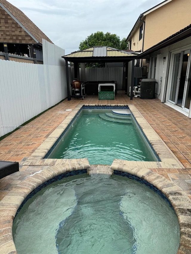 view of pool with an in ground hot tub, a gazebo, and a patio