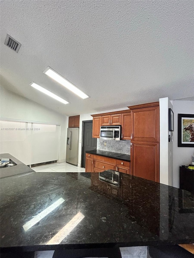 kitchen featuring lofted ceiling, a textured ceiling, stainless steel appliances, and backsplash