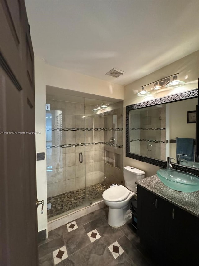 bathroom featuring a shower with door, vanity, and toilet