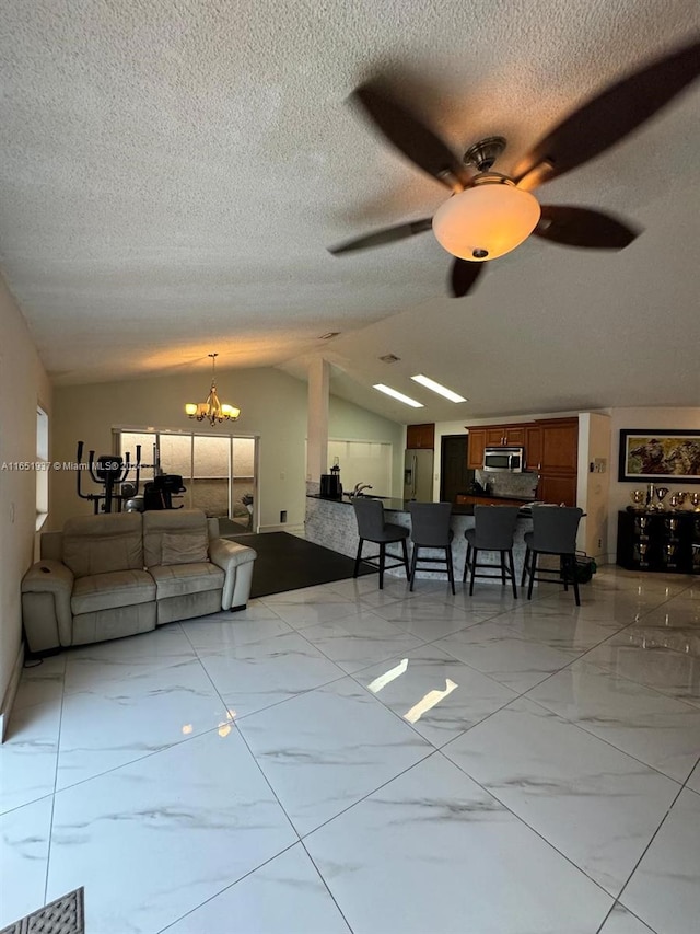 living room featuring vaulted ceiling, a textured ceiling, and ceiling fan with notable chandelier