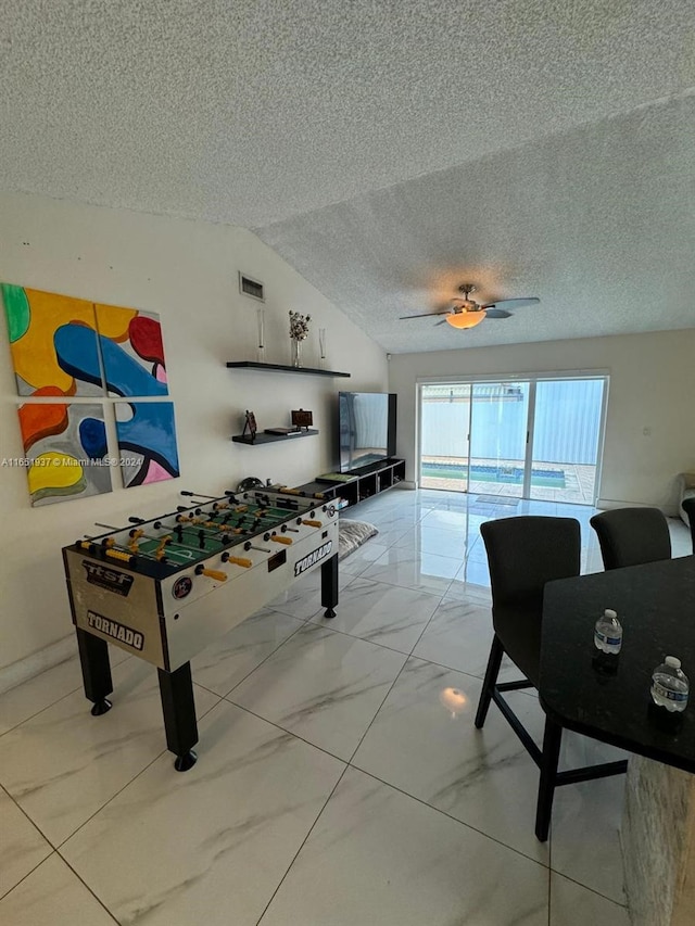 rec room with lofted ceiling, a textured ceiling, and ceiling fan