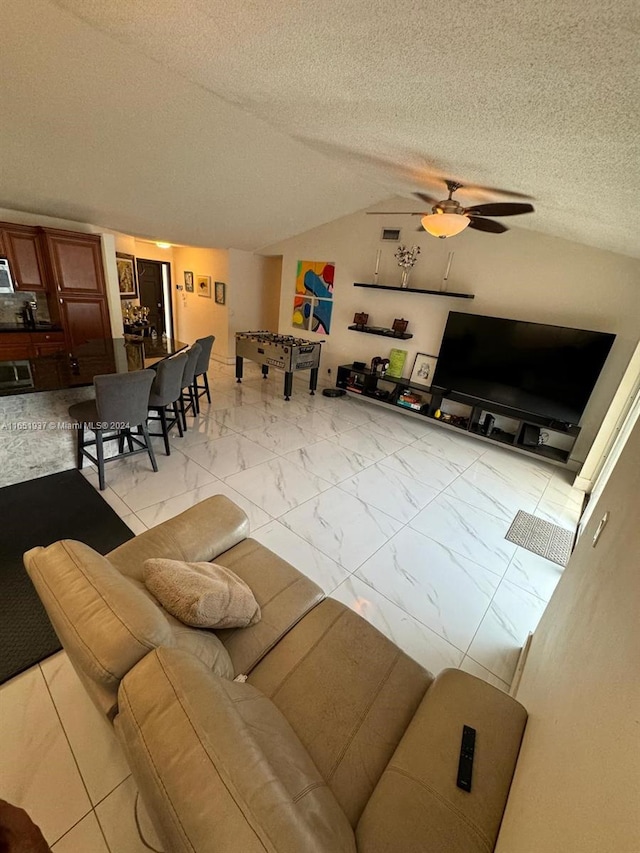 living room with ceiling fan, a textured ceiling, and vaulted ceiling