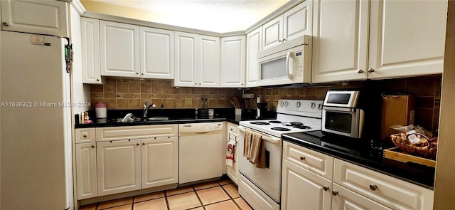 kitchen with white appliances, a textured ceiling, backsplash, sink, and light tile patterned flooring