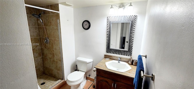 bathroom featuring toilet, a tile shower, and vanity