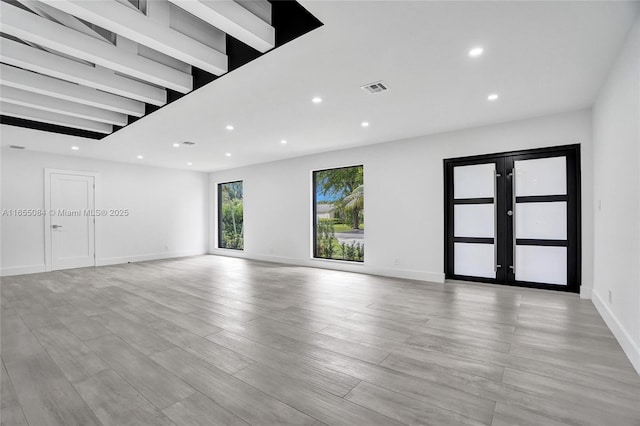 unfurnished living room with french doors and light hardwood / wood-style flooring