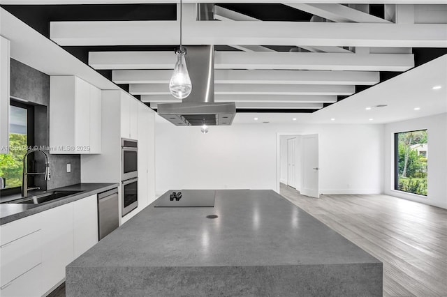 kitchen with hanging light fixtures, white cabinets, sink, and black electric stovetop