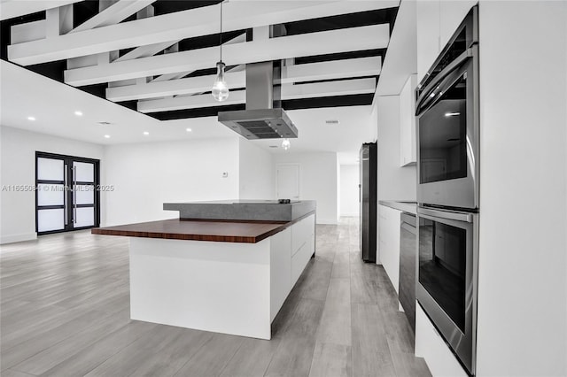 kitchen featuring wooden counters, white cabinetry, hanging light fixtures, stainless steel fridge, and a large island