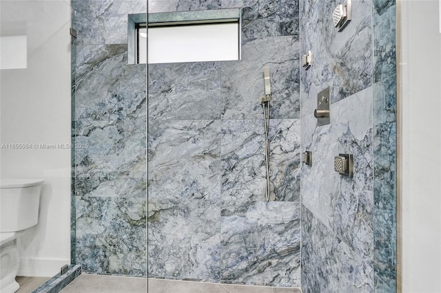 bathroom with tile patterned floors, toilet, and tiled shower