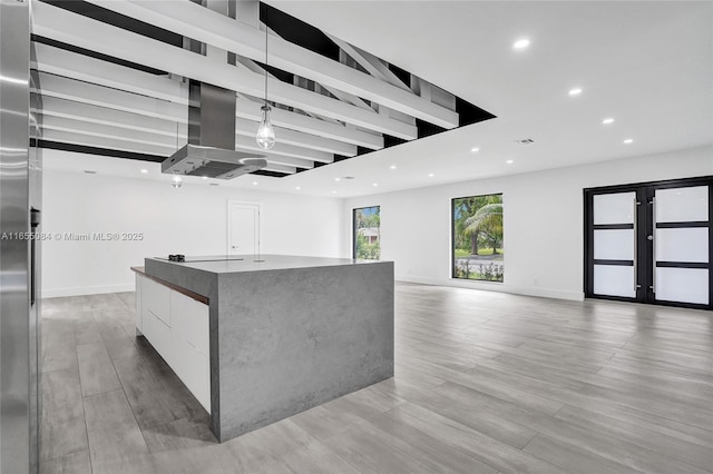 kitchen with light wood-type flooring, white cabinetry, island range hood, and a spacious island