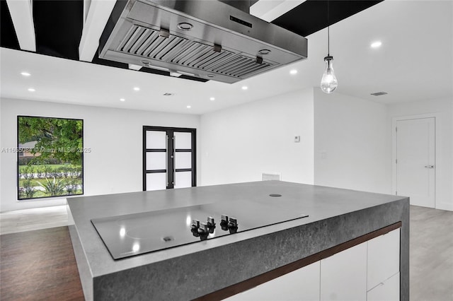 kitchen with ventilation hood, white cabinetry, black electric cooktop, and hanging light fixtures