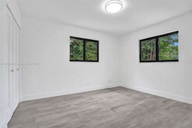 empty room with a wealth of natural light and light hardwood / wood-style floors