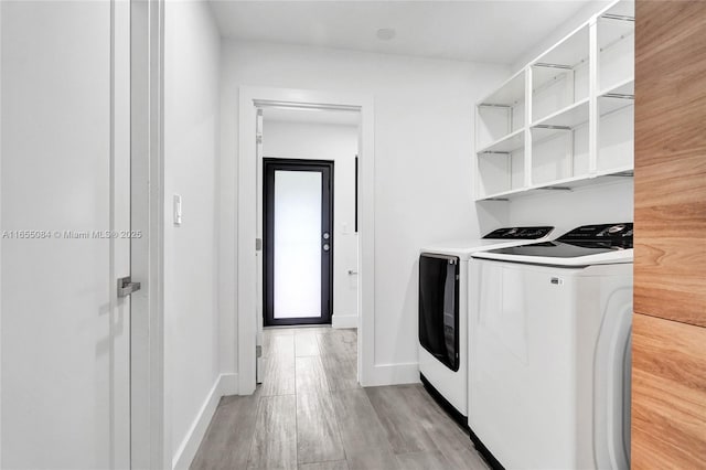 clothes washing area featuring washer and clothes dryer and light wood-type flooring