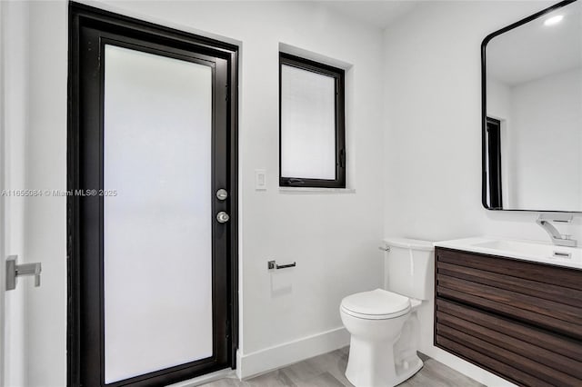 bathroom with toilet, vanity, and hardwood / wood-style flooring