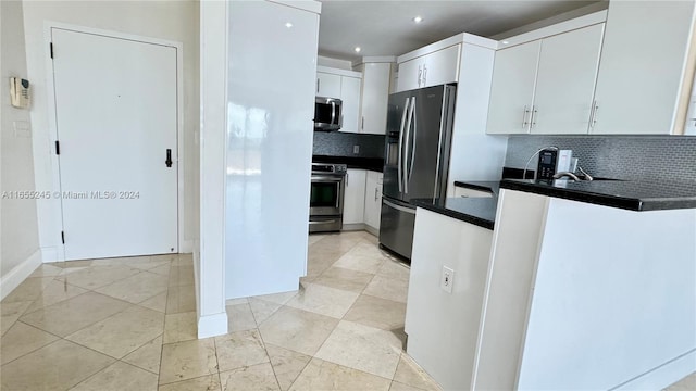 kitchen with appliances with stainless steel finishes, tasteful backsplash, light tile patterned flooring, and white cabinets