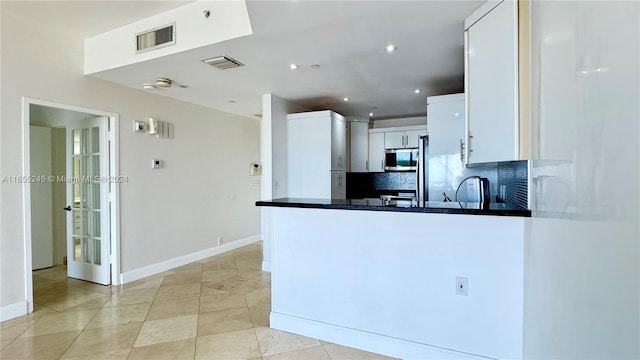 kitchen with white cabinetry, kitchen peninsula, and decorative backsplash