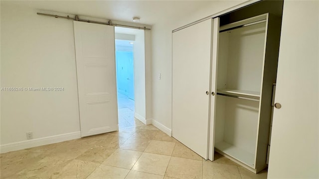 unfurnished bedroom with a barn door and a closet