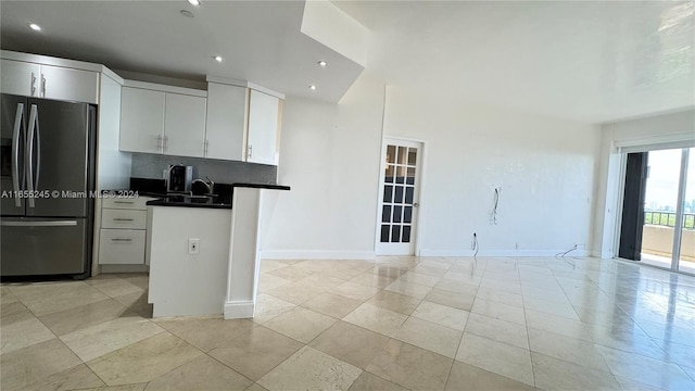 kitchen featuring stainless steel fridge, light tile patterned floors, tasteful backsplash, sink, and white cabinets