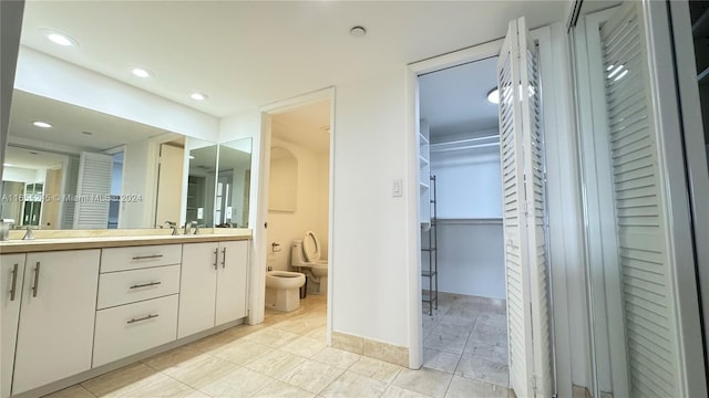 bathroom featuring a bidet, vanity, toilet, and tile patterned flooring