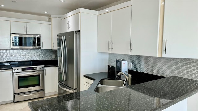 kitchen with appliances with stainless steel finishes, kitchen peninsula, backsplash, and dark stone counters