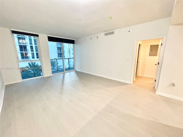 spare room with expansive windows and light hardwood / wood-style flooring