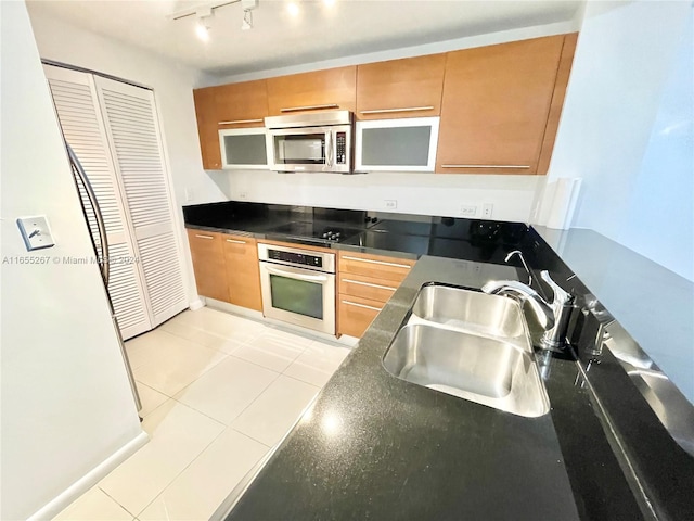 kitchen featuring rail lighting, appliances with stainless steel finishes, light tile patterned flooring, and sink