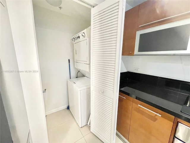 laundry area featuring stacked washer and clothes dryer and light tile patterned floors