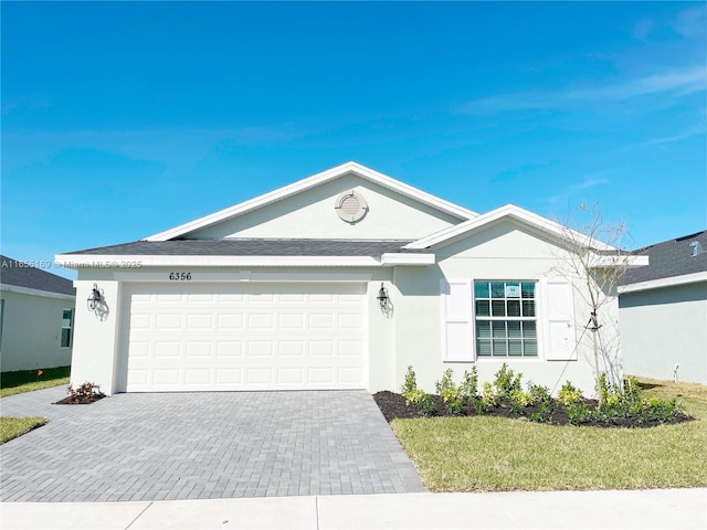 ranch-style home featuring decorative driveway, a garage, and stucco siding