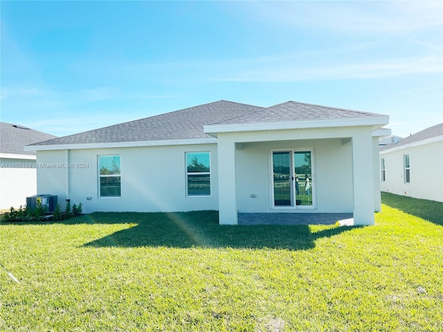 rear view of property featuring central AC unit and a lawn