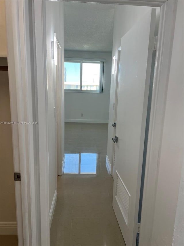 hallway with light tile patterned floors and a textured ceiling