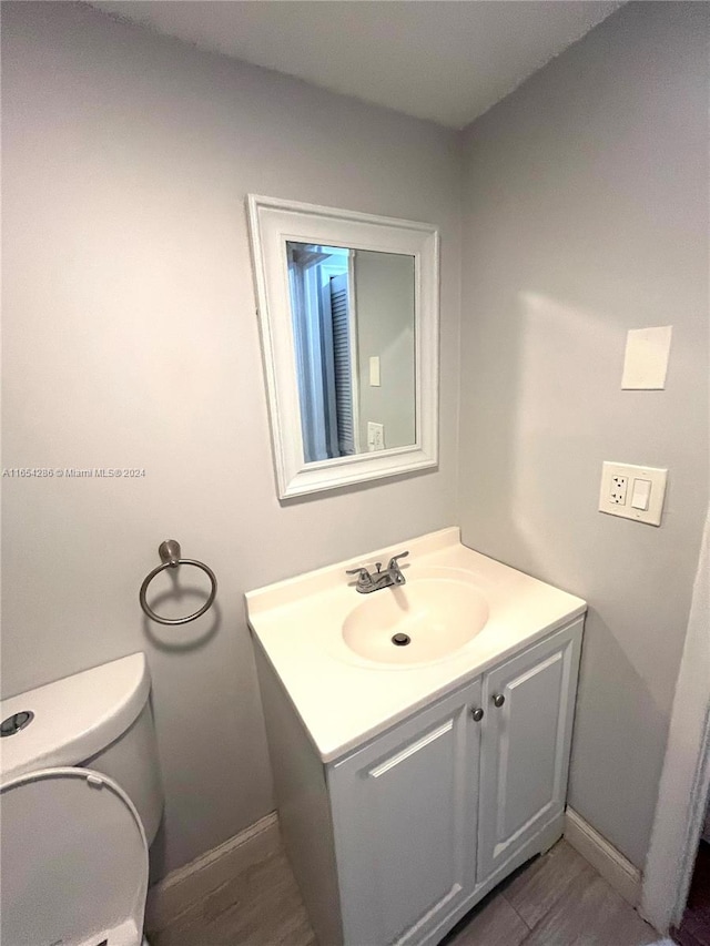 bathroom with vanity, toilet, and hardwood / wood-style flooring