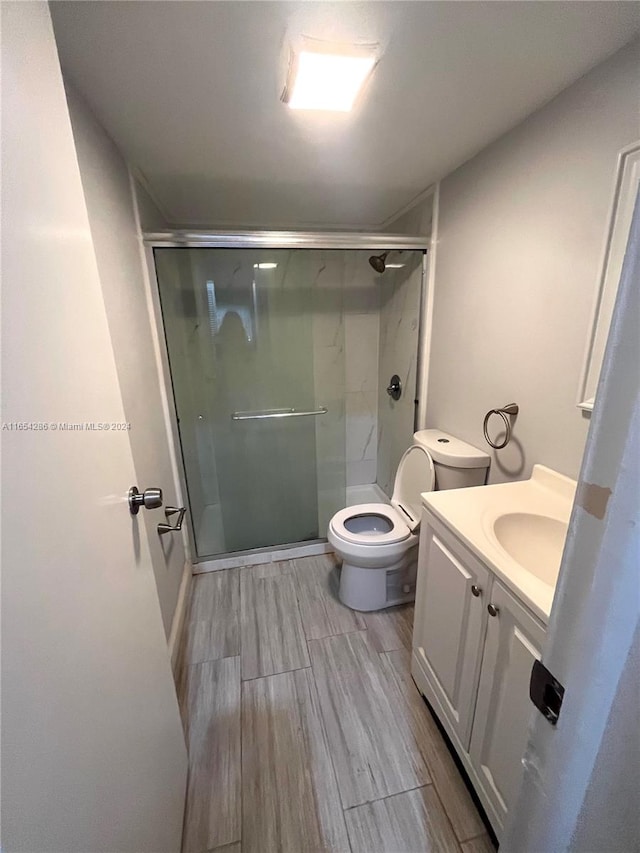 bathroom with vanity, toilet, an enclosed shower, and wood-type flooring