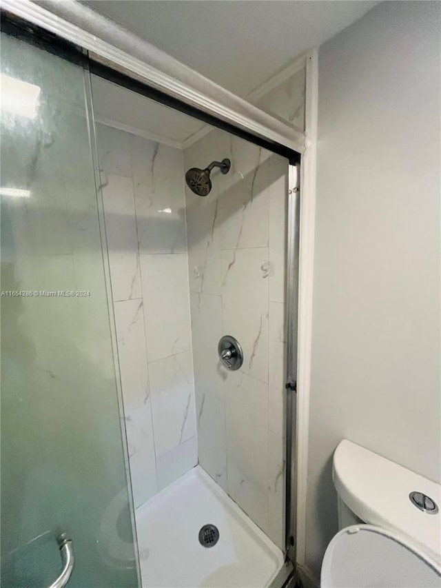 bathroom with toilet and a shower with door