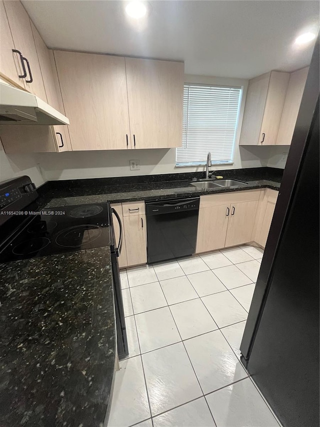 kitchen with dark stone countertops, black appliances, light brown cabinetry, and sink