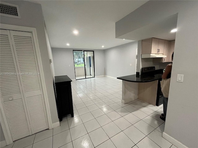 kitchen featuring a breakfast bar area, kitchen peninsula, and light tile patterned flooring