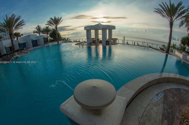 pool at dusk featuring a water view